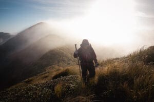 Wanderin im Nebel mit Sonne im Hintergrund.