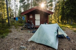 An einsamer Hütte im Wald im Gegenlicht das Zelt von Dan Durston aufgestellt