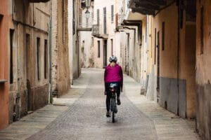 Frau auf Gravelbike fährt durch alte Gassen im Piemont.