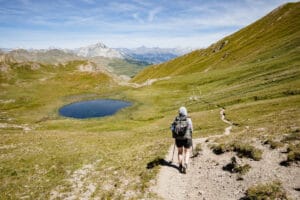 Frau wandert steinigen Weg zum Bergsee hinunter