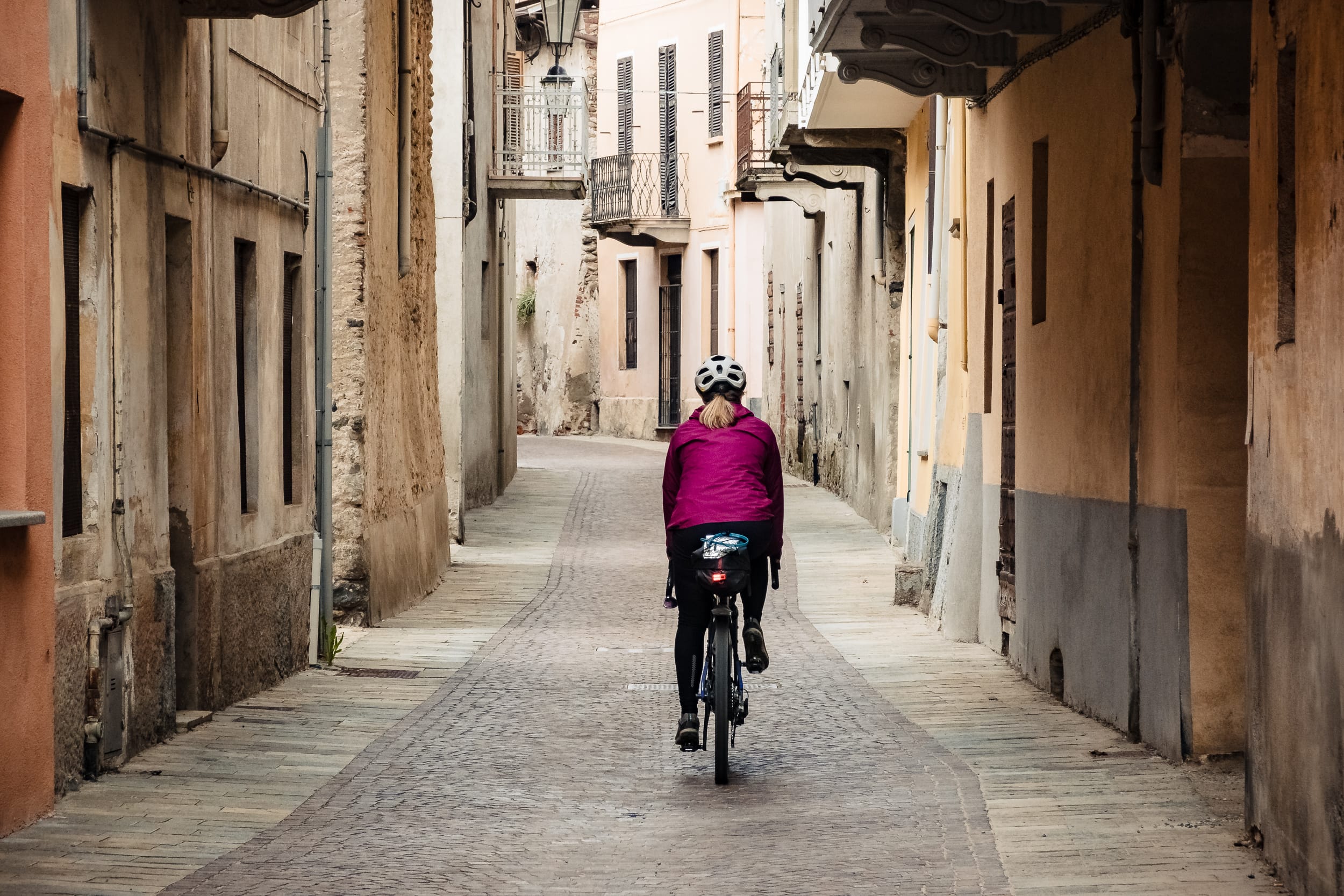 Bikepacking auf dem Gravelbike im Piemont Frau auf Gravelbike durch Altstadt im Piemont